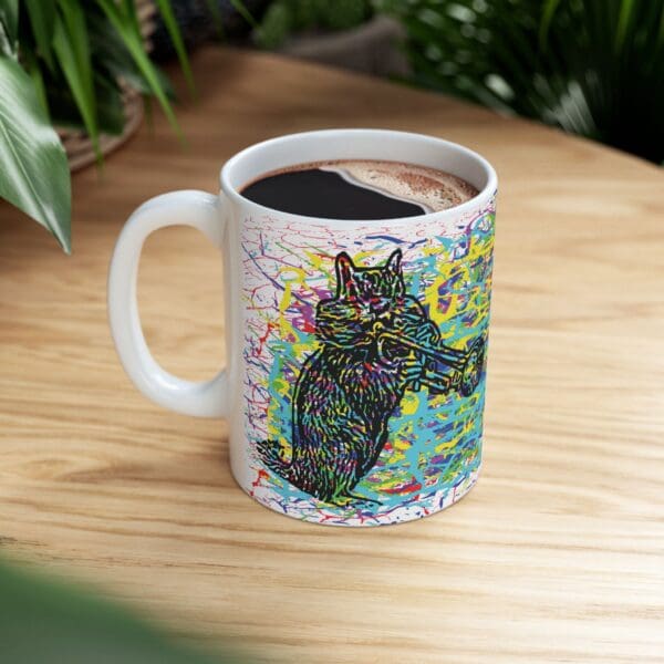 A Cracked Chipmunk Coffee Mug, made from white ceramic and adorned with vibrant artwork of a cat playing a saxophone, contains a dark beverage as it sits on a wooden table with green plants in the background.