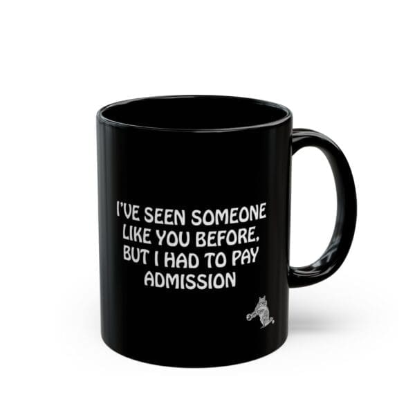 The Admission Coffee Mug features a black design with white text that says, "I've seen someone like you before, but I had to pay admission," and includes a small cartoon character in the bottom right corner.