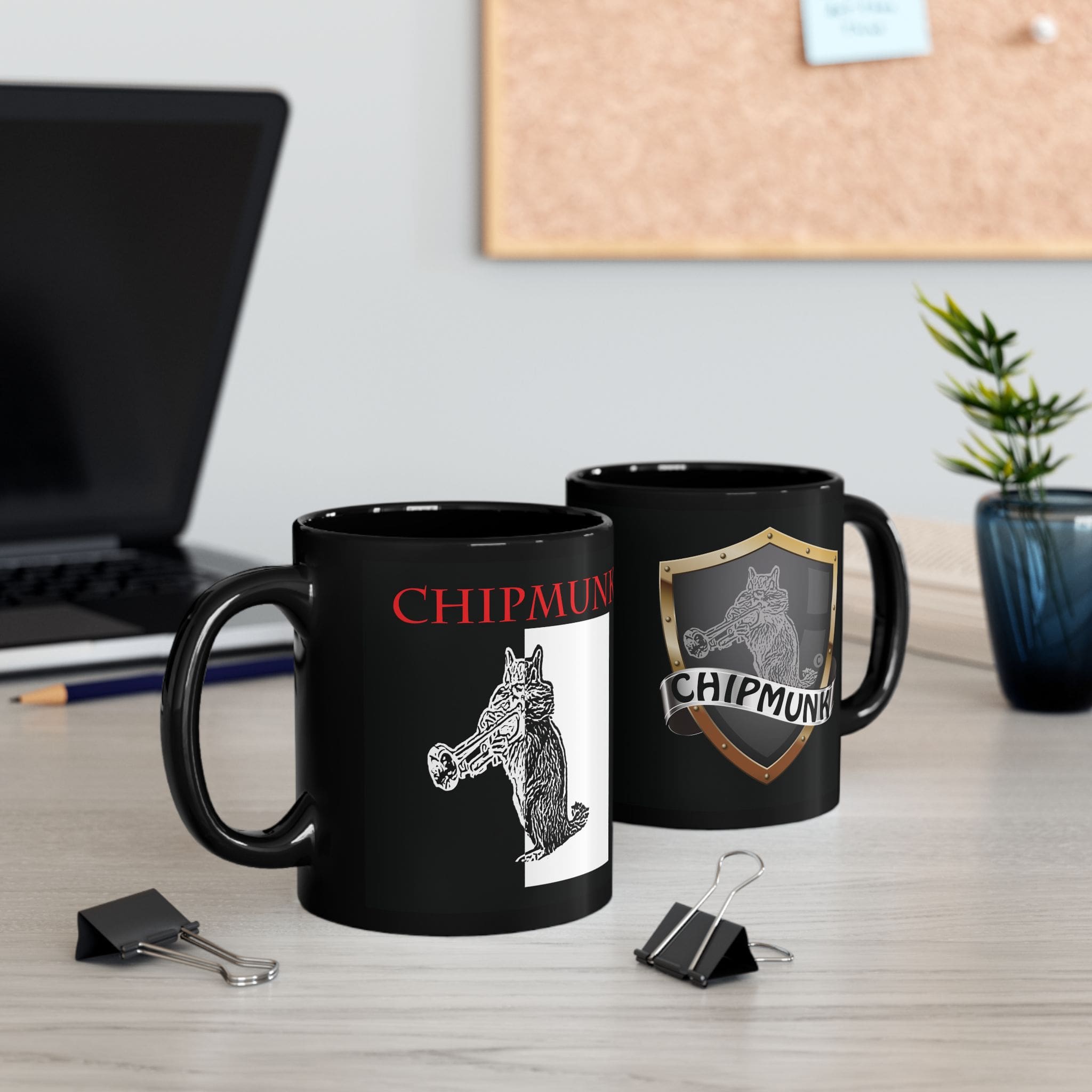 Two Chipmunk Coffee Mugs, featuring a chipmunk illustration and the text "CHIPMUNK," sit on a desk. Nearby are a laptop, plant, paper clips, and a corkboard in the background.