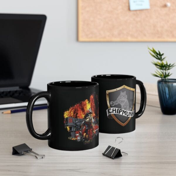 Two black coffee mugs on a desk; one is the Firetruck Coffee Cup, featuring a firefighter design with flames, and the other has a shield emblem with the word "Chipmunk." Office supplies and a plant are also on the desk.