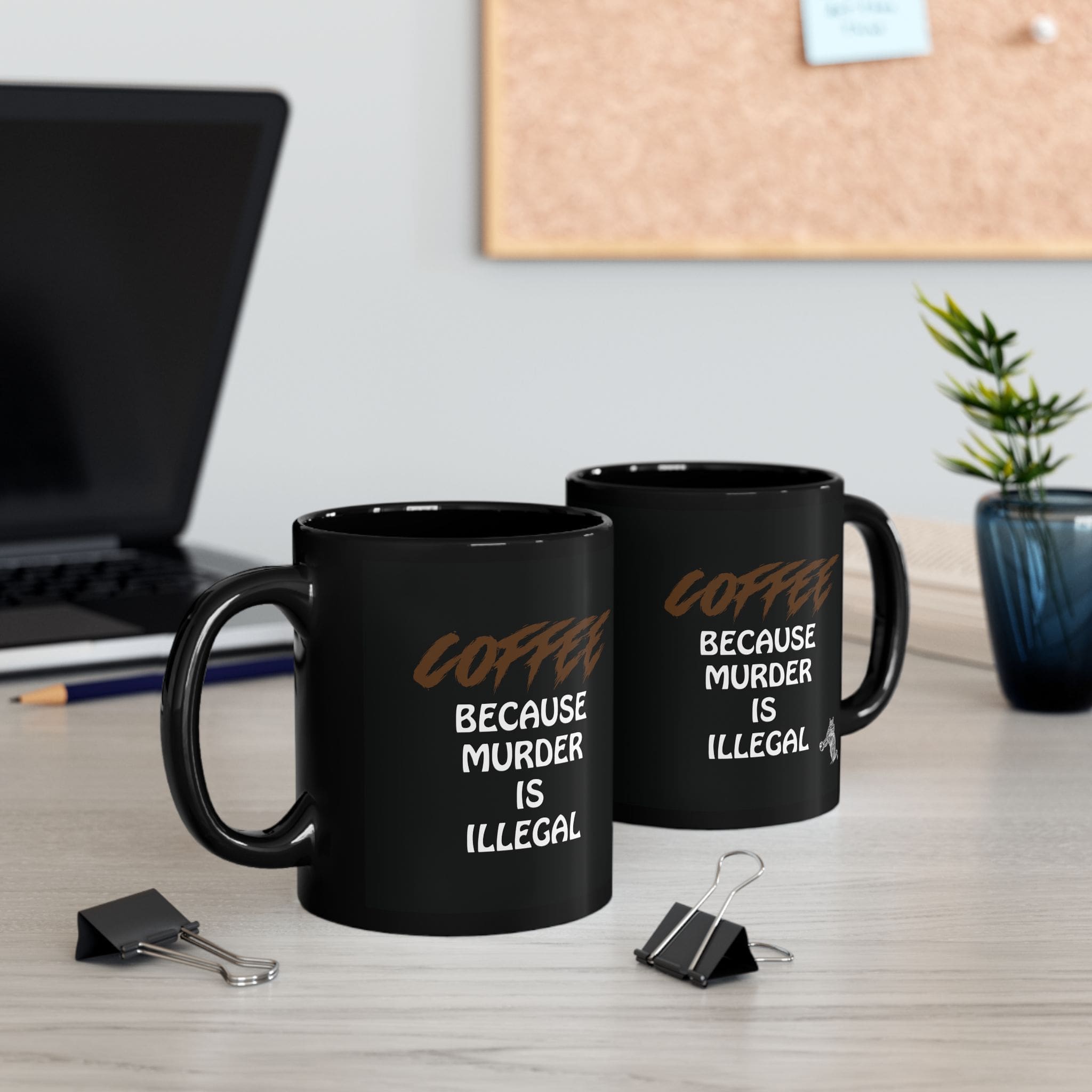 Two "Coffee Because Murder Is Illegal" coffee mugs sit on a desk. In the background, there is a laptop, binders, a plant, and a corkboard.