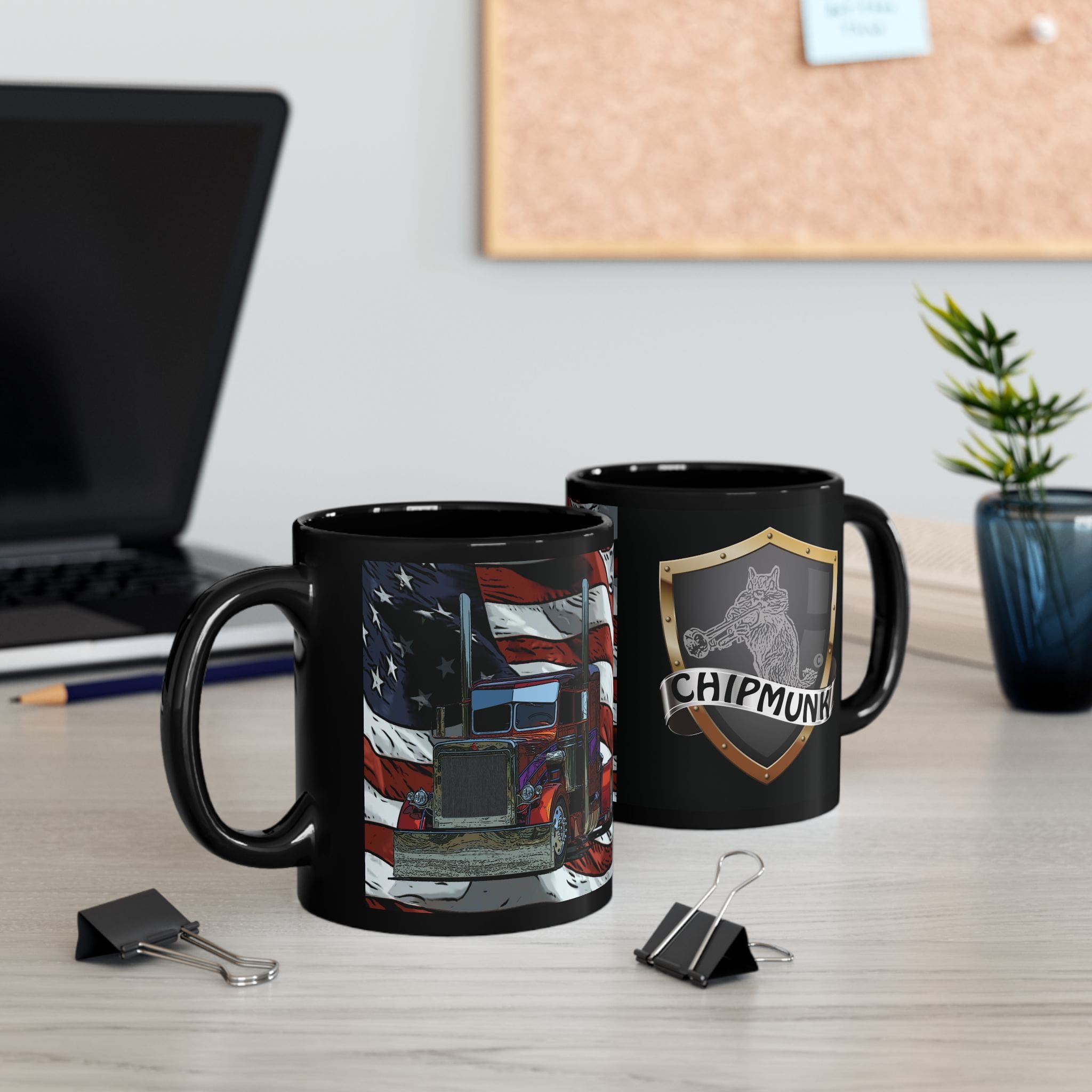 Two black mugs on a desk with binder clips. One mug is the "American Trucker Coffee Cup," featuring an American flag and truck design, while the other displays a "CHIPMUNK" logo with a shield and chipmunk. There's a laptop and bulletin board in the background.