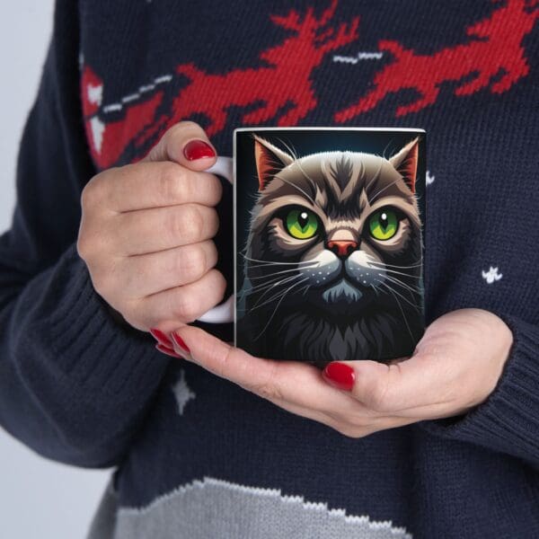 Person holding an Angry Cats Coffee Mug 11oz, while wearing a dark sweater with red reindeer designs.