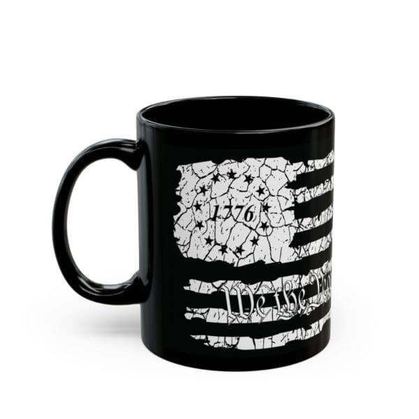 The American Pride Coffee Mug is a black mug featuring a distressed white American flag design, with "1776" on the flag and "We the People" written at the bottom.