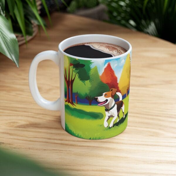 The Playful Dog Coffee Mug 11oz, filled with coffee, is on a wooden surface. The white ceramic mug features a colorful illustration of a happy dog in a vibrant outdoor setting with trees and a lake.