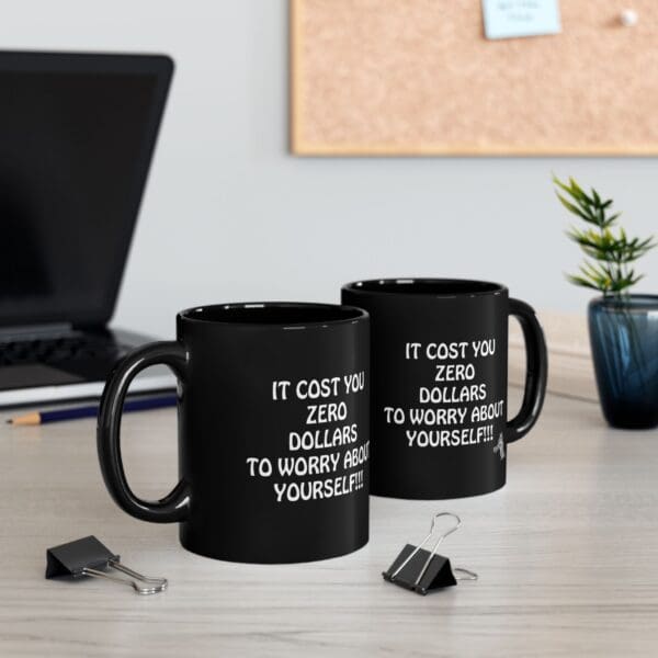 Two Zero Dollars Coffee Mugs with the text "IT COST YOU ZERO DOLLARS TO WORRY ABOUT YOURSELF!!" stand on a desk with binder clips, a laptop, and a potted plant in the background.