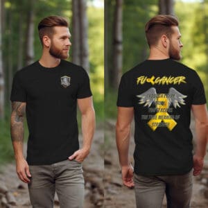 A man is wearing the F Cancer Childhood Cancer Awareness T-Shirt, which features a shield logo on the front and text addressing cancer on the back. The shirt has yellow and white print with a wing design, and he's standing in a wooded outdoor setting.