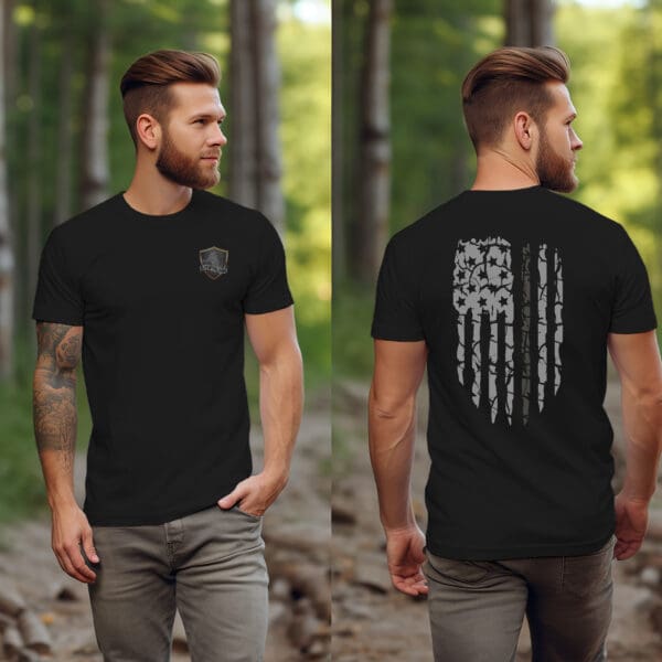 A man with tattoos, wearing a Correctional Officer Support T-Shirt featuring a shield logo on the front and an American flag design on the back, stands on a path in a wooded area.