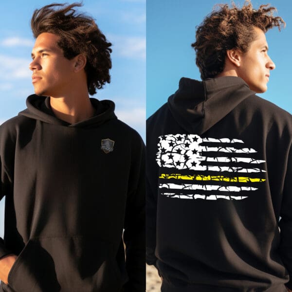 A person wearing the Dispatcher Support Hoodie, featuring a small crest logo on the front and a stylized flag design on the back. They are outdoors with a blue sky in the background.