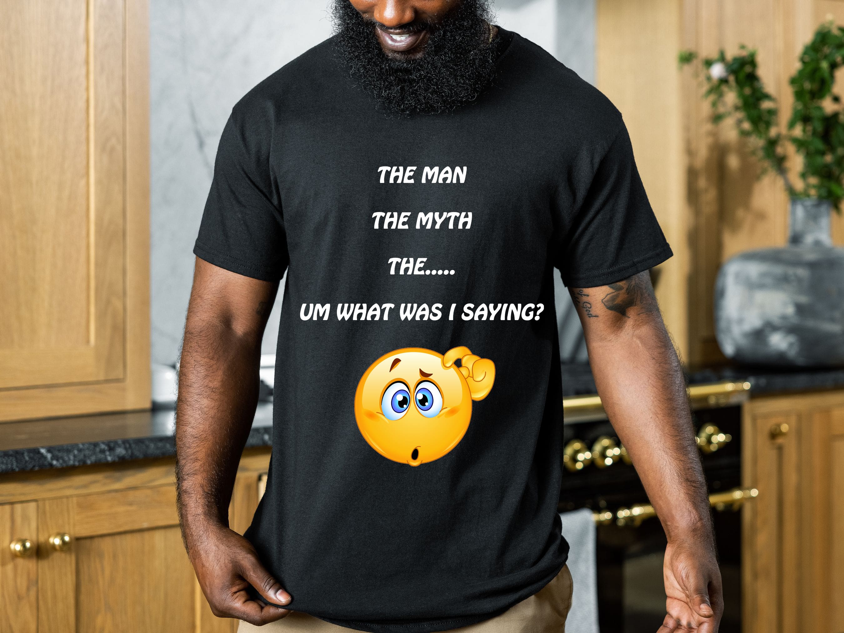 A person wearing "The Man T-Shirt" in black, featuring the text "THE MAN THE MYTH THE... UM WHAT WAS I SAYING?" and an emoji of a confused face.