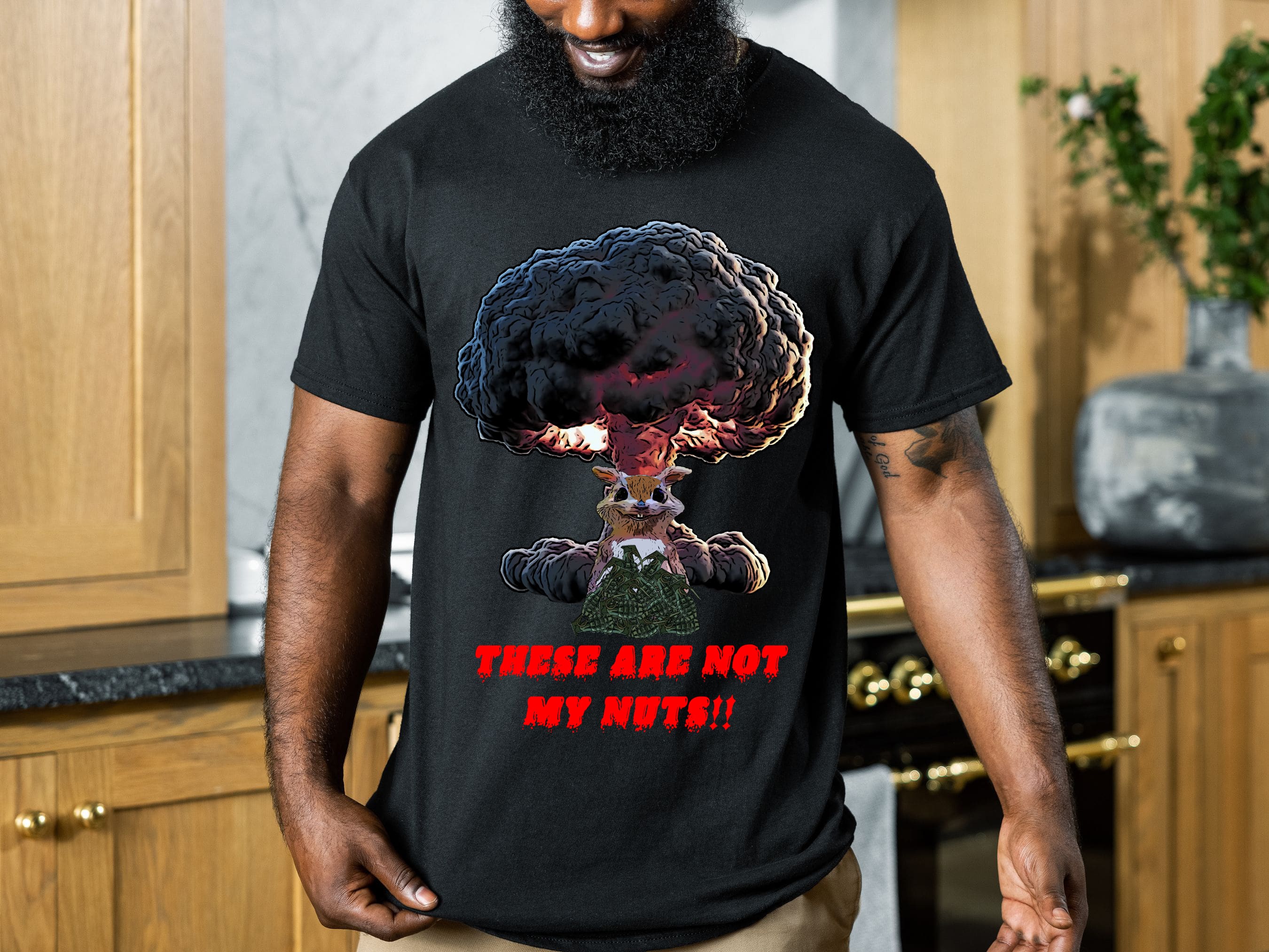 A man wearing the "Not My Nuts T-Shirt," which features a cartoon squirrel and a mushroom cloud with the caption "THESE ARE NOT MY NUTS!!" in red text, stands in a kitchen.