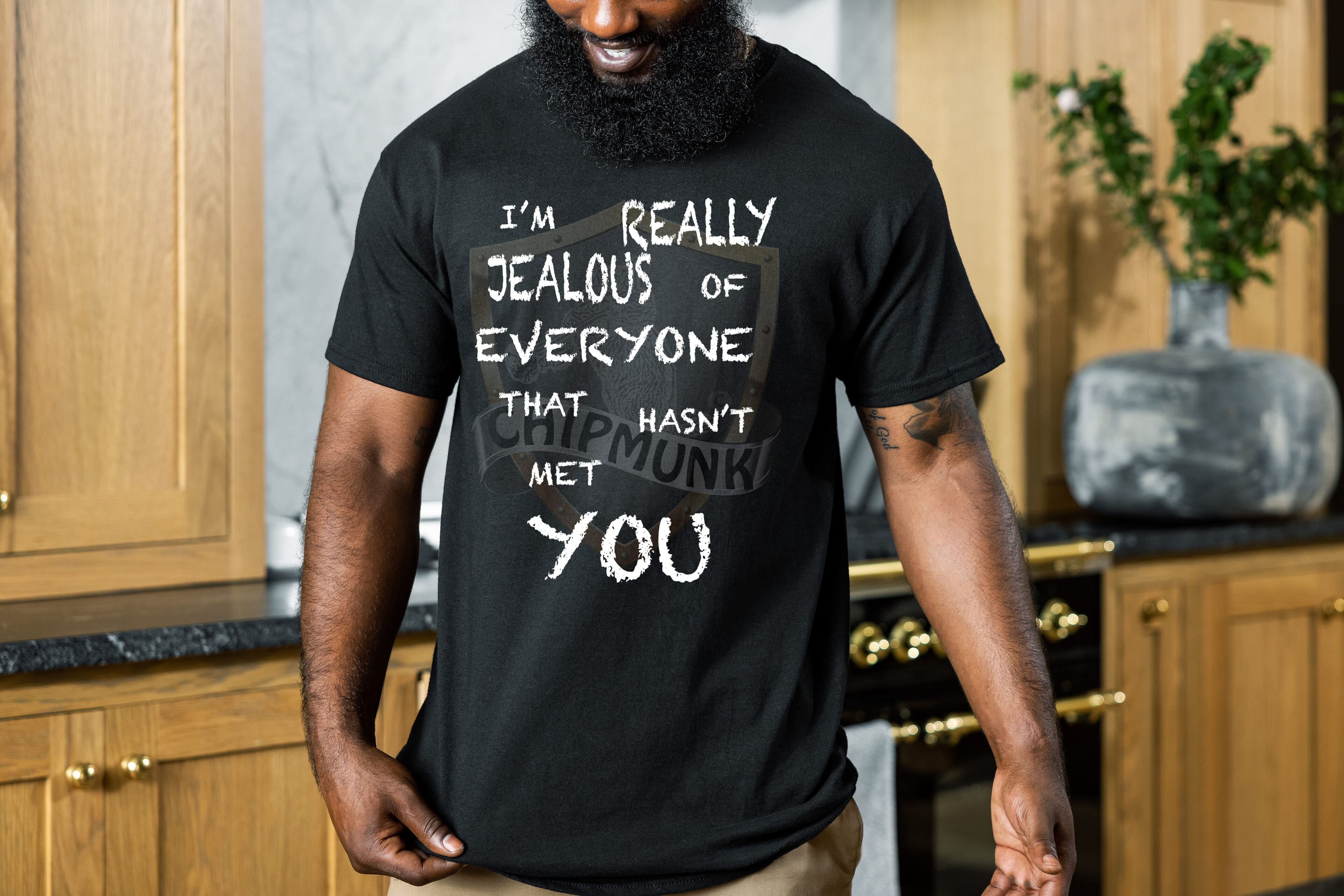 A person wearing the Jealous T-Shirt, which has the text "I'm really jealous of everyone that hasn't met you," is standing in a kitchen.