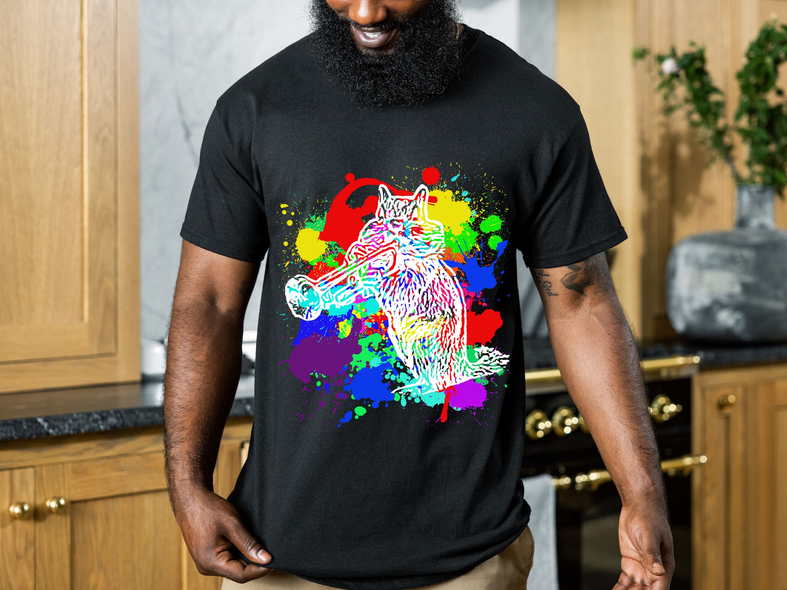 A person wearing a Splash Chipmunk T-Shirt with a colorful, abstract design of a wolf holding a megaphone is standing in a kitchen.