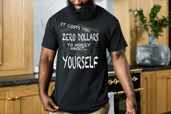 A man wearing a Zero T-Shirt that reads "It costs you zero dollars to worry about yourself" is standing in a kitchen.