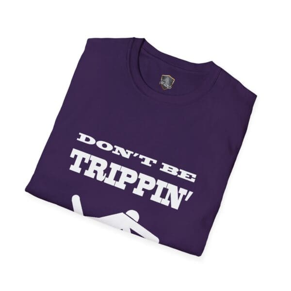 A folded "Don't Be Trippin'" T-Shirt in dark purple featuring white text and a stick figure slipping.