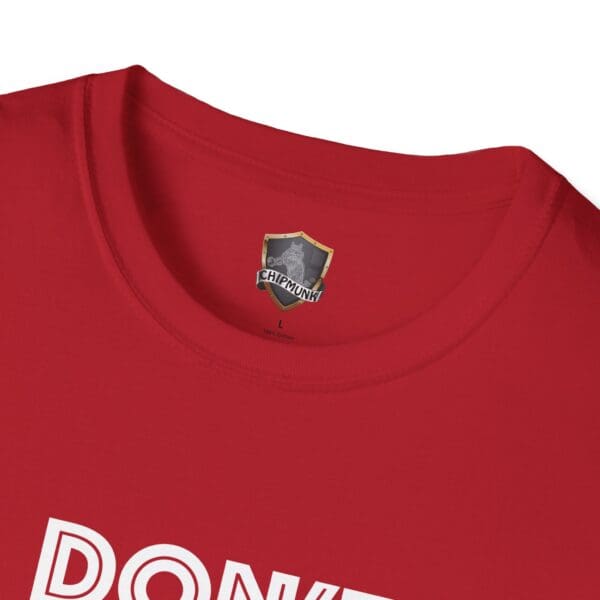 Close-up of the "Don't Be A... Tee," featuring bold white "DONKEY" lettering on a red shirt. A shield logo with "CHIPMUNK" is located near the collar.