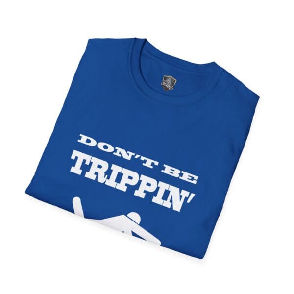 A folded "Don't Be Trippin'" T-Shirt in blue, featuring white lettering and a graphic of a person slipping.