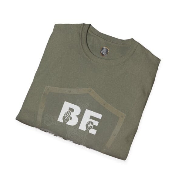 Folded green T-shirt named "Be Kind in Sign Language," featuring a shield design with the word "BE" in large letters and hands gesturing above the text.