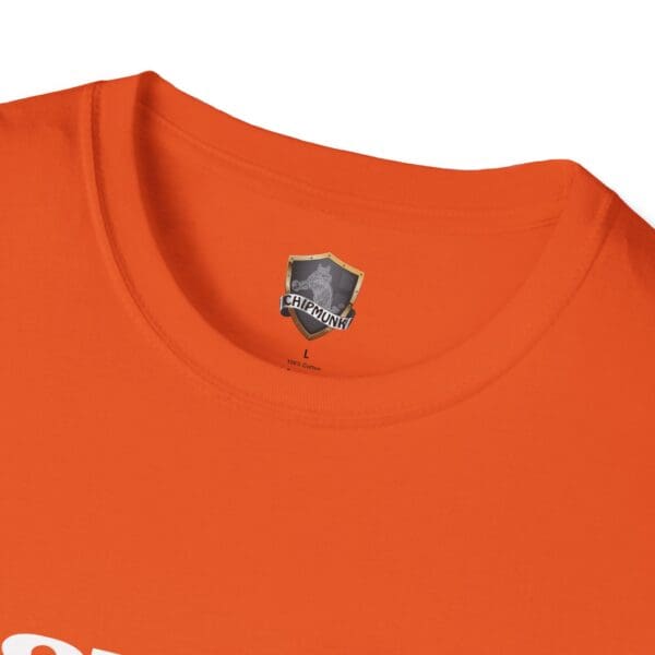 Close-up of a "Don't Be Trippin'" T-shirt in orange, featuring a label with a shield logo and the text "Chipmunk" printed below the neckline.