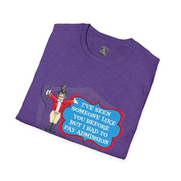 A folded Admission T-Shirt in purple, featuring a cartoon ringmaster with a whip and the text, "I've seen someone like you before but I had to pay admission.