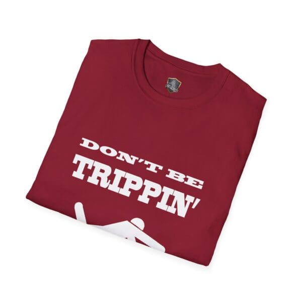 A folded red "Don't Be Trippin'" T-Shirt featuring white text and an image of a stick figure slipping.