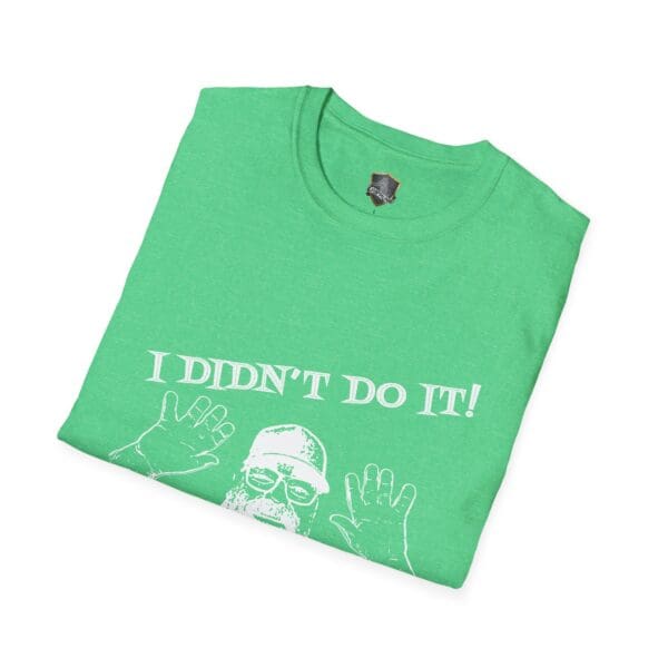 A folded green T-shirt featuring a graphic of George the Roadie with raised palms, accompanied by the text "I Didn't Do It! I Was Framed!!!".