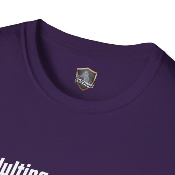 Close-up of a purple Adulting 1-Star Review T-Shirt showing a visible label with a shield design and the word "CHIPMUNK" beneath the back collar. Partially visible white text appears at the bottom.