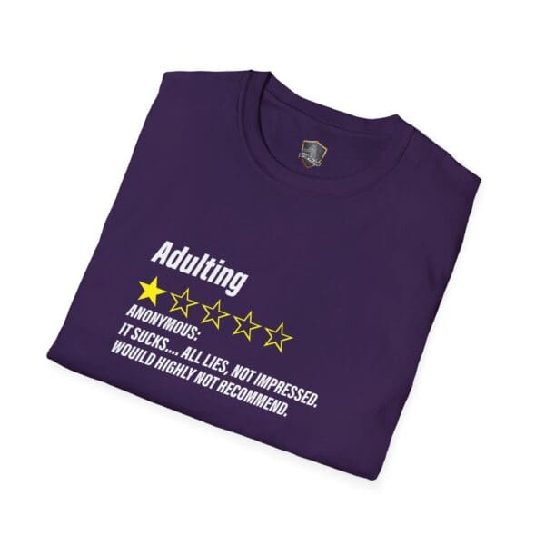 A folded purple t-shirt with white text and yellow stars says: "Adulting 1-Star Review T-Shirt: It sucks... All lies, not impressed. Would highly not recommend.