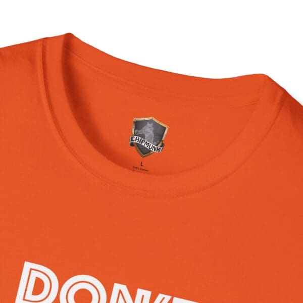 Close-up of an orange "Don't Be A... Tee" featuring a neckline tag with a shield logo and the word "Chipmunk.