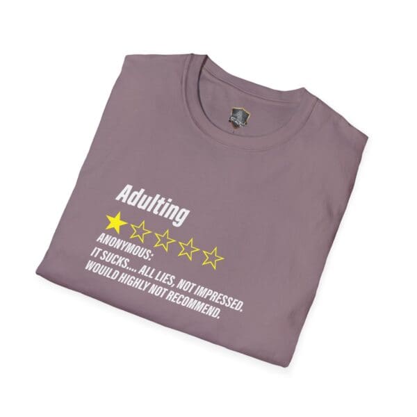 A folded Adulting 1-Star Review T-Shirt in purple featuring printed text: "Adulting - 1 star. Anonymous: It sucks... All lies. Not impressed. Would highly not recommend.