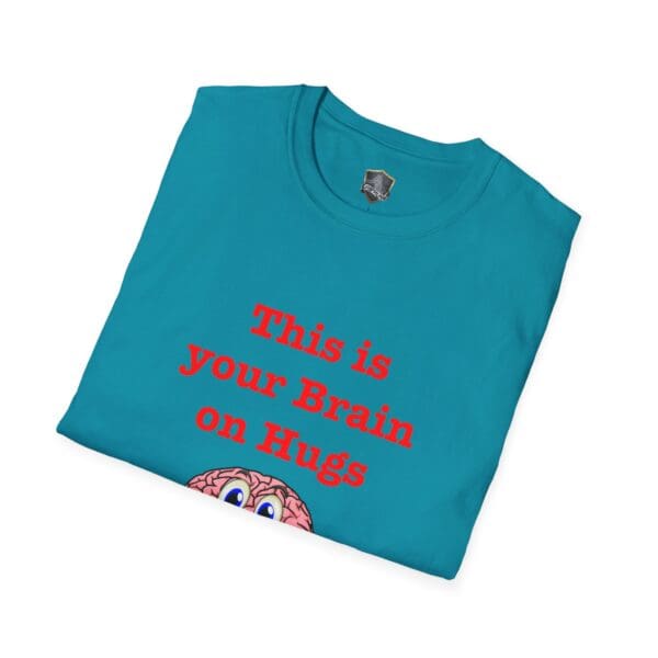 A folded 'This is Your Brain on Hugs T-Shirt' in blue, featuring red text and a partially visible cartoon brain at the bottom.