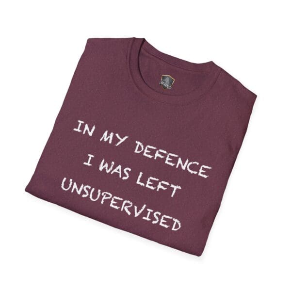 A folded Unsupervised Mischief T-Shirt, featuring the phrase "IN MY DEFENCE I WAS LEFT UNSUPERVISED" printed in white capital letters on maroon fabric.