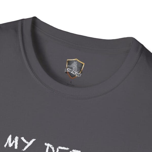 Close-up image of a dark gray T-shirt with the "Unsupervised Mischief" logo on the inside label and partially visible white text on the outside reading "MY DEF.