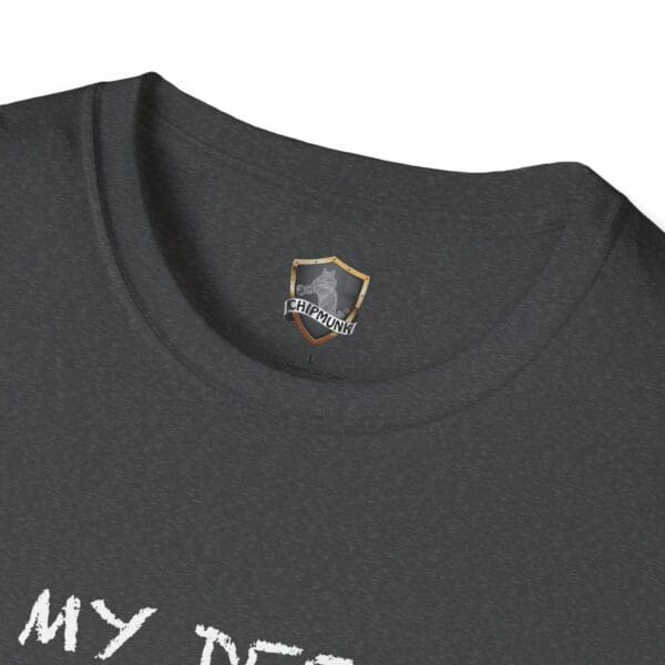 A close-up of a dark gray Unsupervised Mischief T-Shirt reveals the neckline and an inner tag featuring a Chipmunk logo and emblem. The shirt displays partially visible text reading, "MY DEE.