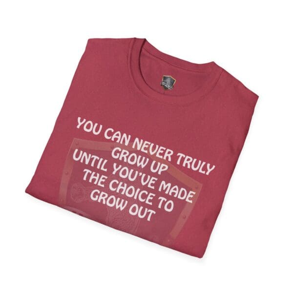 A folded red "You Can Never Truly Grow Up" t-shirt with the text, "You can never truly grow up until you've made the choice to grow out.