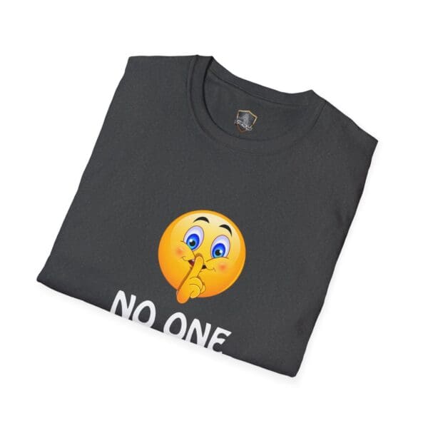 A folded T-shirt in black featuring a shushing emoji and partially visible text from the "No One Cares T-Shirt.