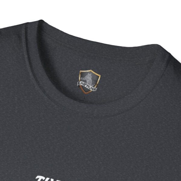 Close-up of the collar of The Man T-Shirt in dark gray, adorned with a small gray shield emblem displaying the word "Chipmunk" at its center.