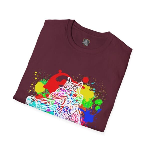 A folded Splash Chipmunk T-Shirt in maroon, adorned with a vibrant print of a cat playing a trumpet, featuring splashes of blue, yellow, and green.