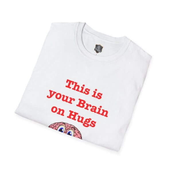 The 'This is Your Brain on Hugs' T-shirt is folded and white, showcasing red text that says "This is your Brain on Hugs," along with a brain graphic.