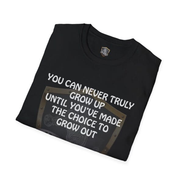 A folded "You Can Never Truly Grow Up" black t-shirt with the text "You can never truly grow up until you've made the choice to grow out" printed on it.