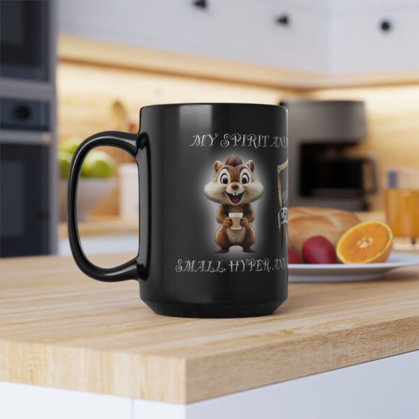 Black "My Spirit Animal Is a Chipmunk" coffee mug, featuring a cartoon chipmunk with the text: "small, hyper, and cute." Kitchen background includes fruit and a blurred toaster. Available in 11oz and 15oz sizes.