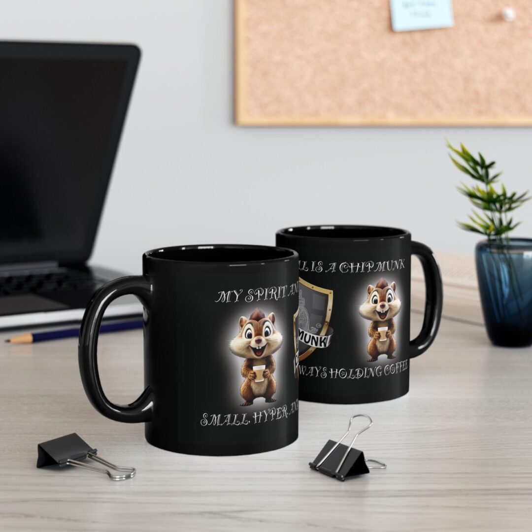 Two "My Spirit Animal Is a Chipmunk" black mugs (11oz, 15oz) with humorous text sit on a desk alongside a plant, laptop, and binder clips.